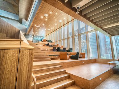 Modern tiered lounge with wood stairs, built-in seating, and floor-to-ceiling windows overlooking th