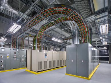 Industrial electrical room with switchgear cabinets and color-coded overhead cable trays.