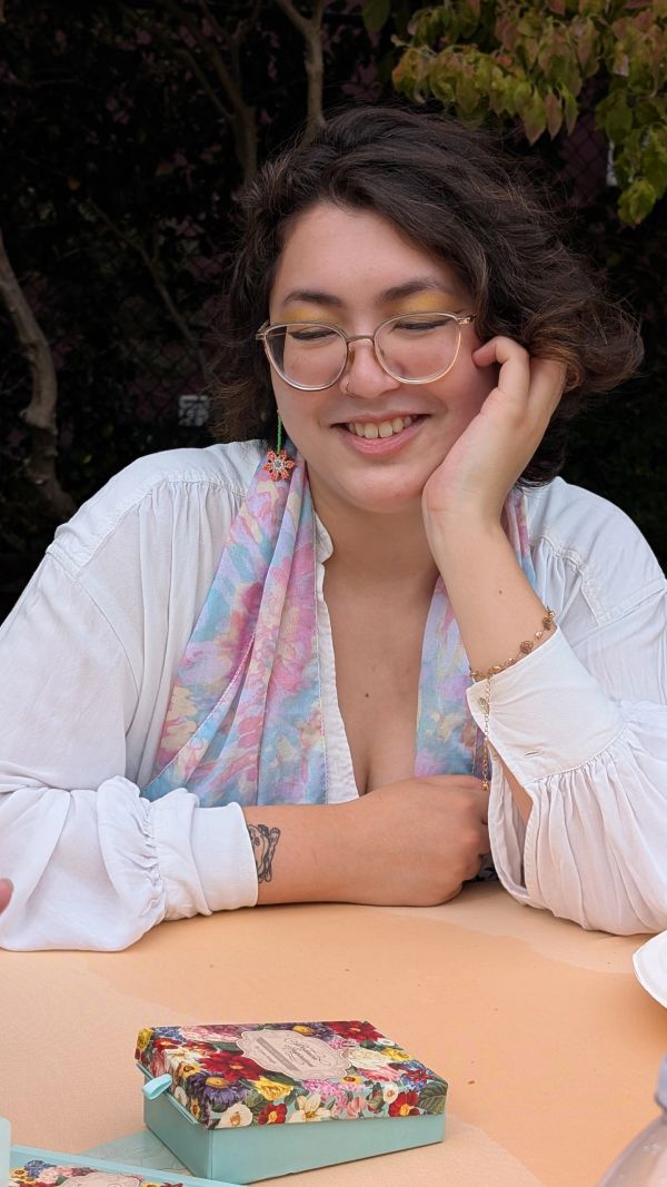A smiling woman with glasses sitting at a table.