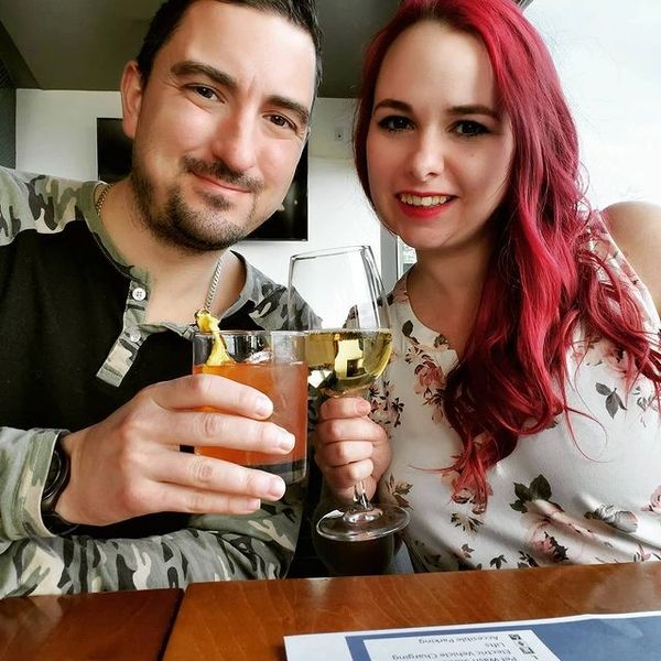 a man holding a pink drink and a women with red hair holding a glass of white wine