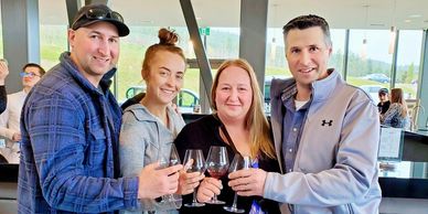 4 people posing for a picture holding wine glasses