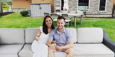 two people drinking wine on a white couch outside