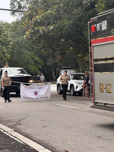 Veterans march holding a banner honoring veterans during a parade.