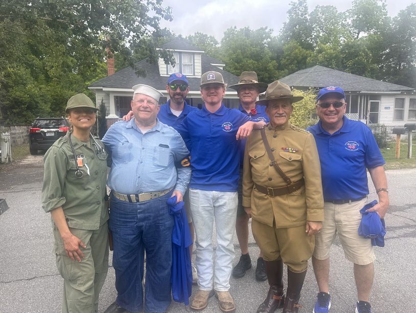 Group of people in military and casual attire posing outdoors.