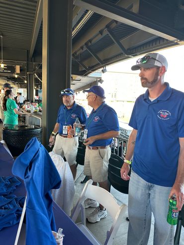 Three men in blue shirts at an outdoor event.