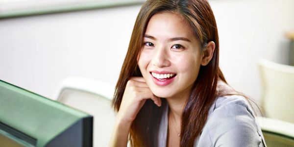 Smiling woman sitting at a desk with a computer.