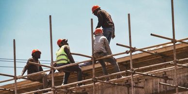 Construction workers wearing helmets and safety vests on scaffolding.