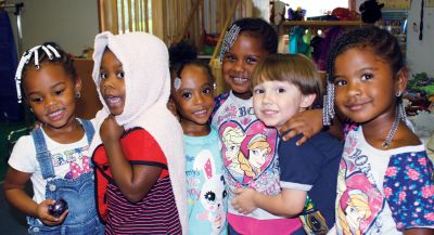 Group of kids smiling and posing together indoors.