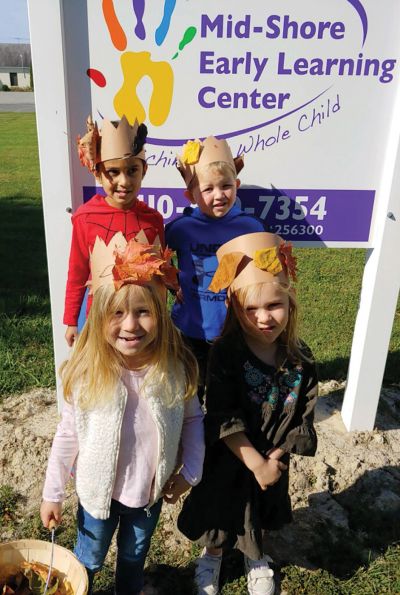 Children wearing paper crowns with leaves at a learning center.