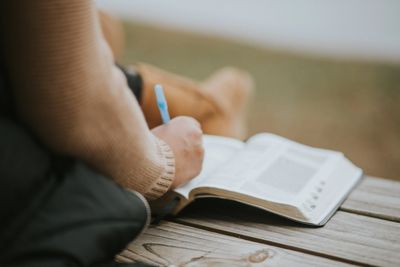 Woman sitting and highlighting Bible