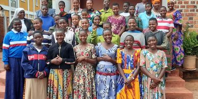 A large group of smiling women and girls standing together outdoors.