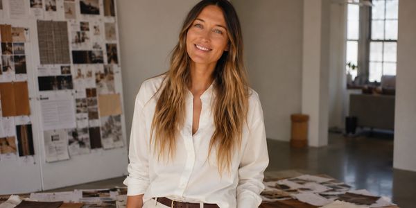 Smiling woman in white shirt standing in a creative studio space.