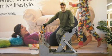 Woman laughing on exercise machine with man assisting and colorful socks in motion.
