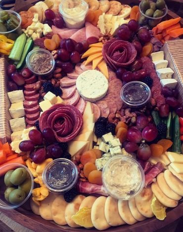 A colorful charcuterie board with meats, cheeses, fruits, nuts, and dips.