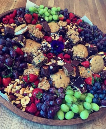 A vibrant platter with assorted fruits, nuts, cookies, and brownies.