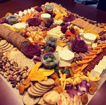 A large, colorful charcuterie board with cheeses, meats, fruits, nuts, and crackers.