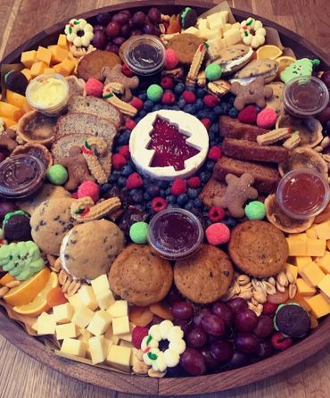 Festive holiday charcuterie board with cheeses, cookies, fruits, and jams.