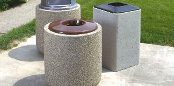 concrete trash receptacles with different colored lids on a concrete sidewalk.
