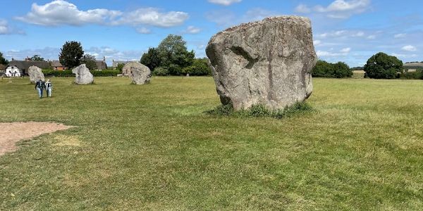 Large standing stones in a grassy field under a partly cloudy sky.