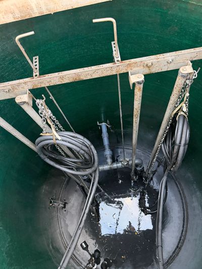Inside view of a green cylindrical tank with grinder pumps