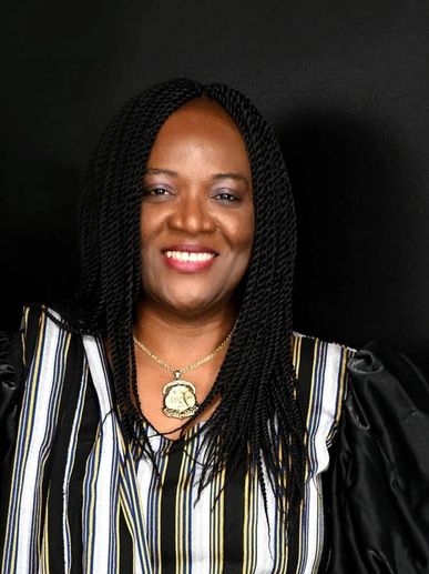 Smiling woman with braided hair wearing a striped top and pendant necklace.