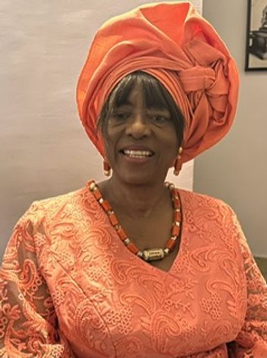 Smiling woman in traditional orange attire and headwrap.