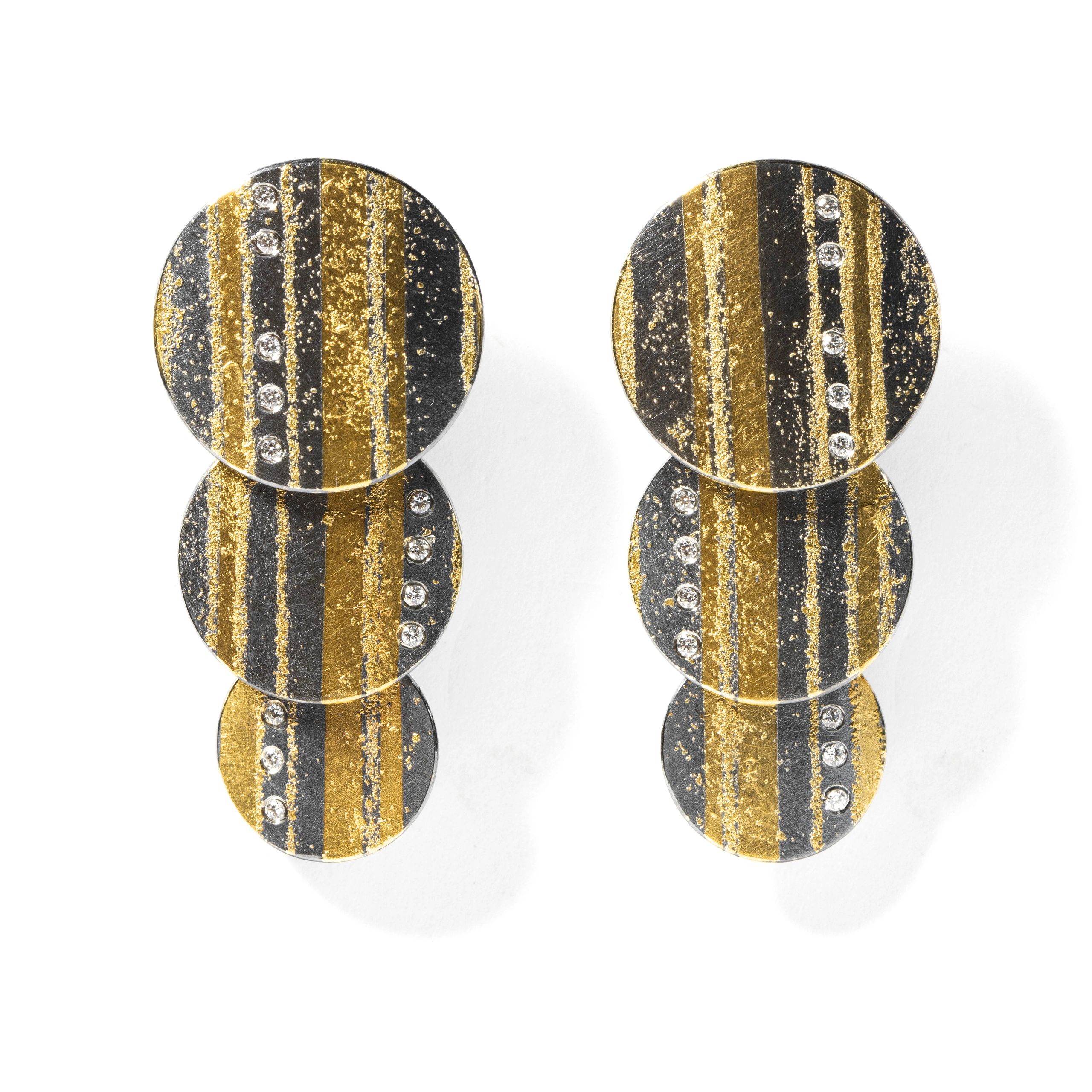 Elegant round earrings with gold and black stripes and embedded crystals.