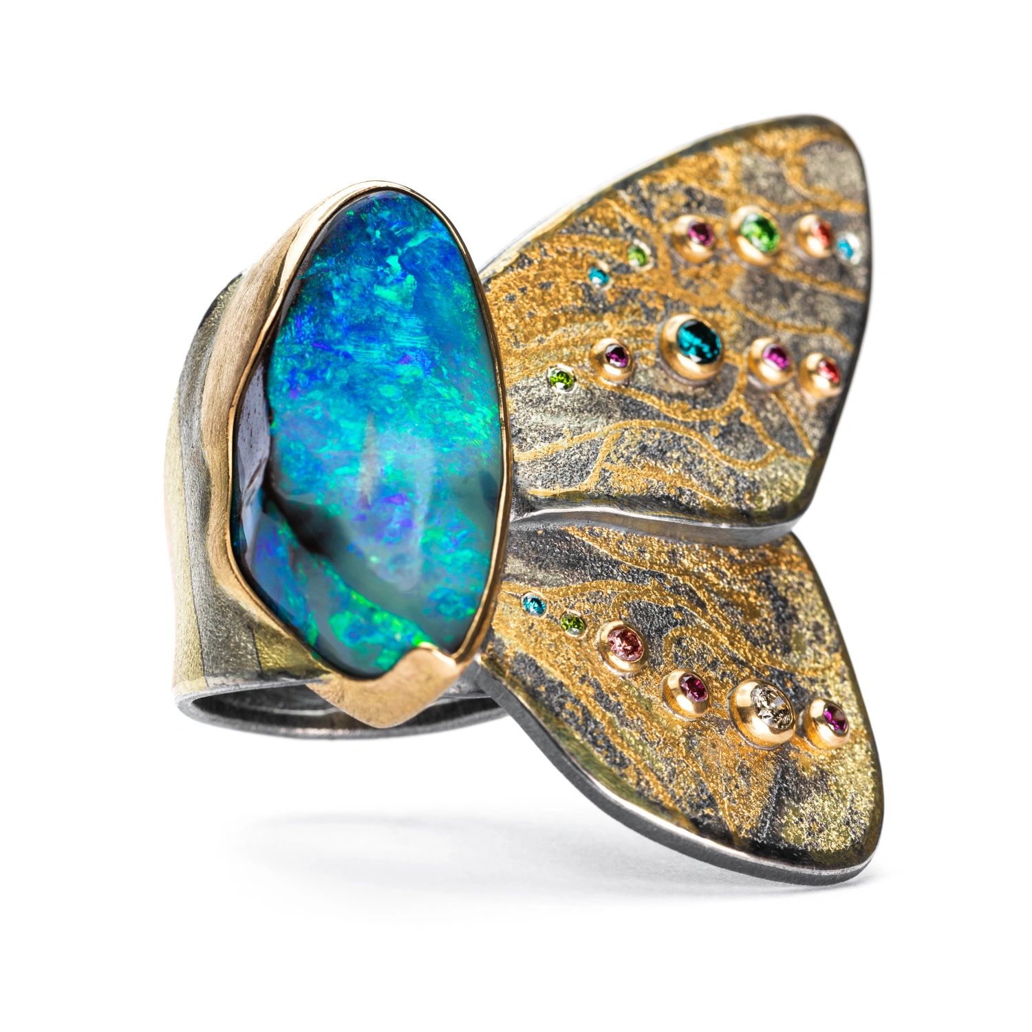 Artistic ring with a large blue gemstone and intricate gold and silver design.