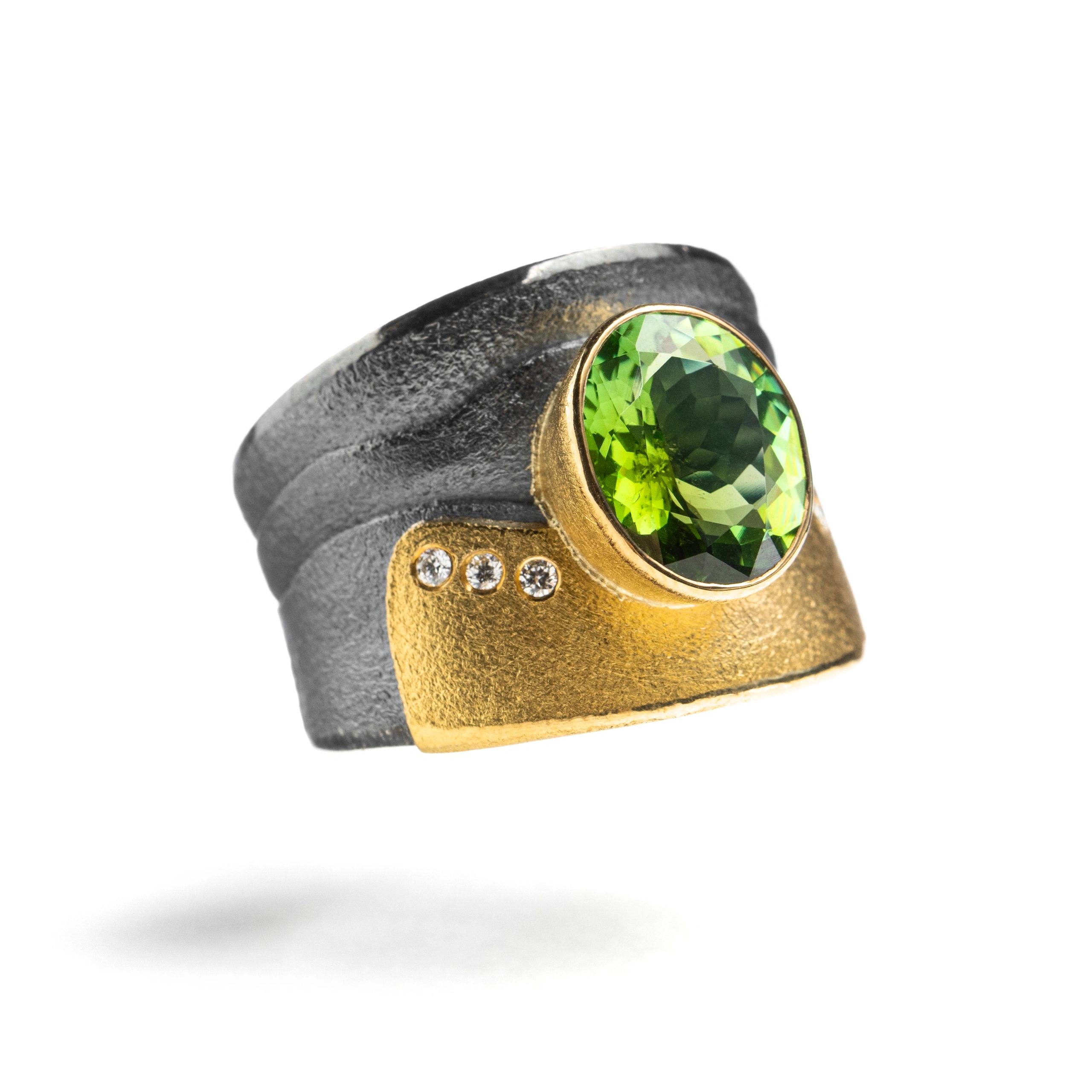 Black and gold ring with green gemstone and small diamonds.