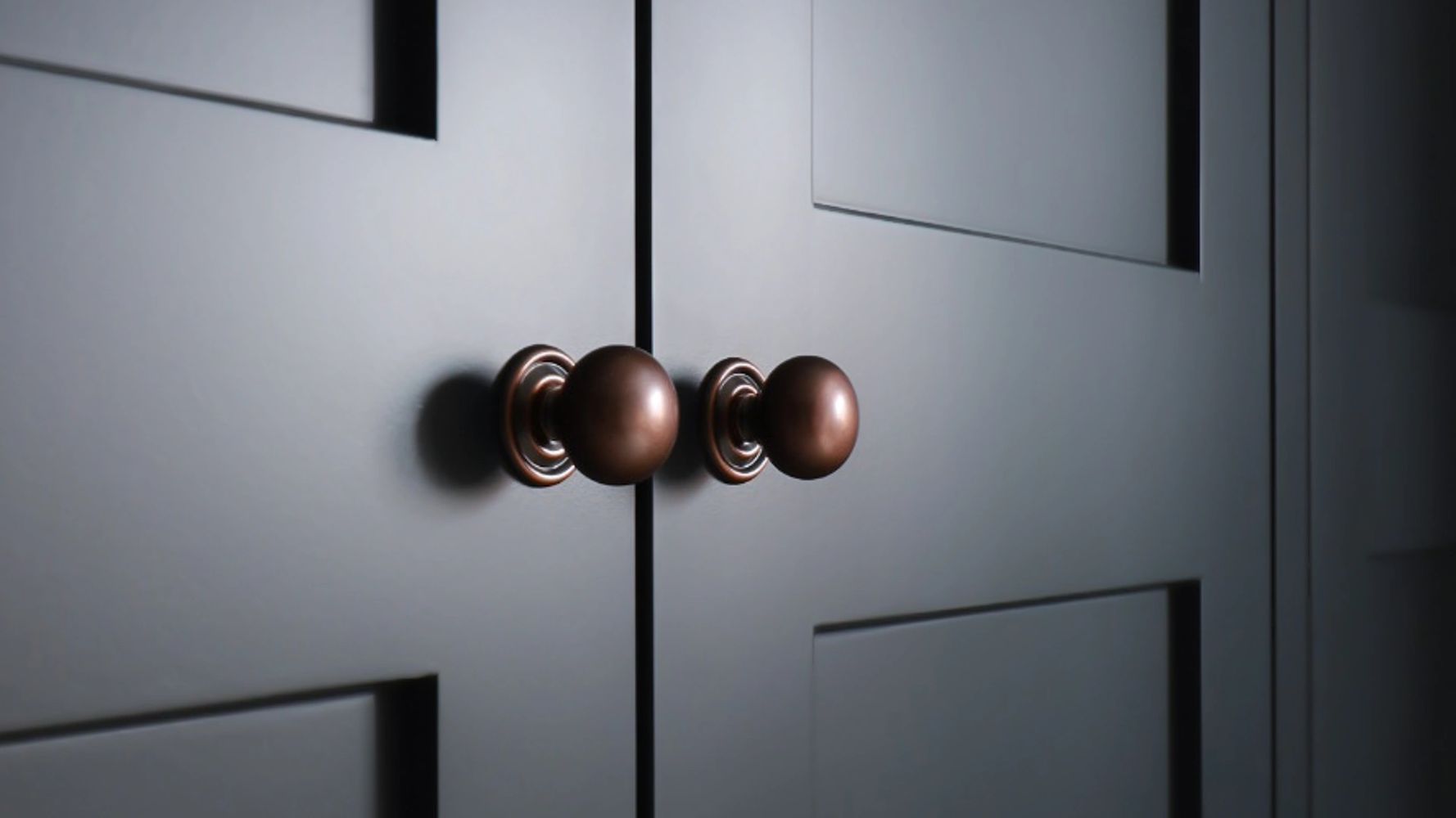 Anitique copper handles on navy blue shaker wardrobes.