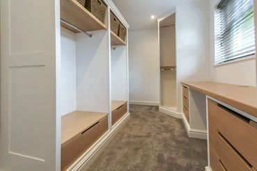 White shaker dressing room with oak drawers.