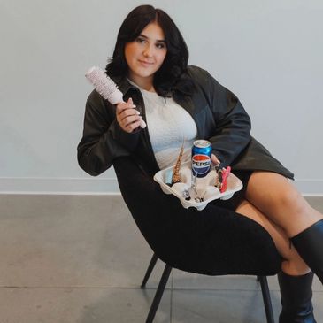 Woman sitting on chair holding a hairbrush and a tray with ice cream cones and a Pepsi can.