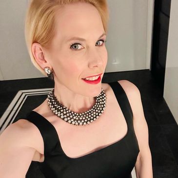 A woman wearing black suit and looking on the camera