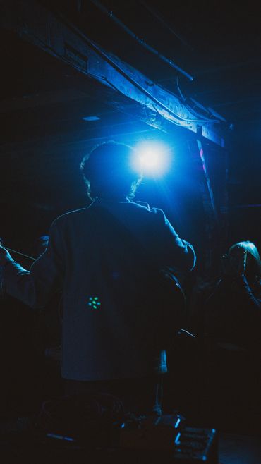 Silhouette of a musician playing guitar under blue stage light.
