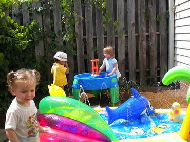 Pic 1.
3 daycare toddlers playing in a backyard. Two kids are playing at a water table.