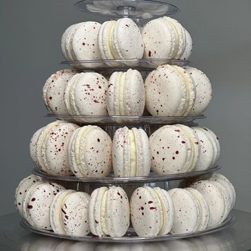 Tiered display of white macarons with red speckles.