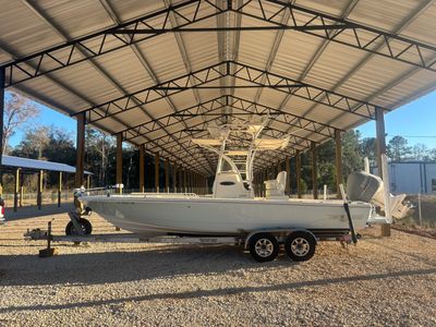 White Pathfinder boat on trailer under metal canopy in a gravel lot.