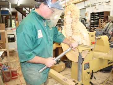 Man using a lathe to carve wood.
