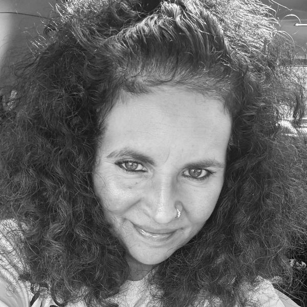 Black and white portrait of a woman with curly hair and a nose ring.