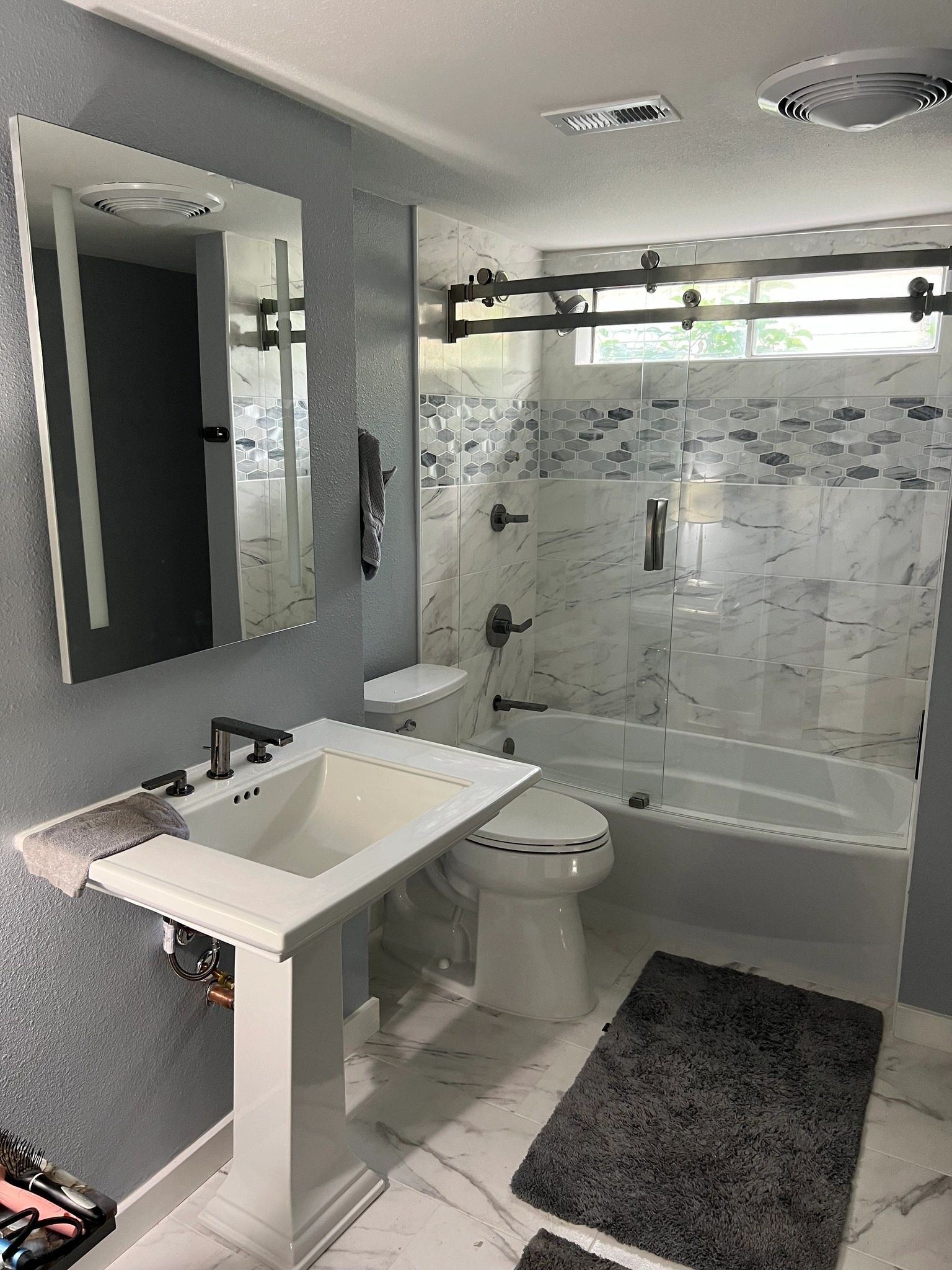 Modern bathroom with marble tiles and glass shower doors.
