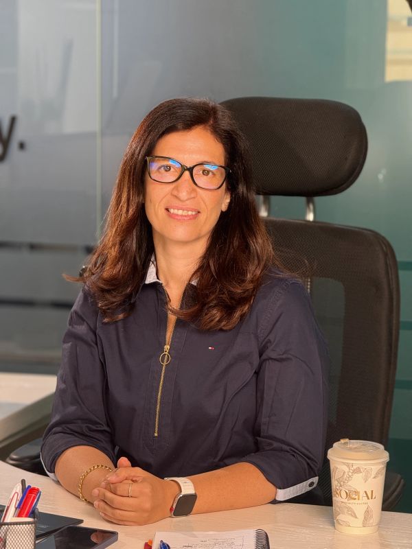 Woman sitting at desk smiling with coffee cup.