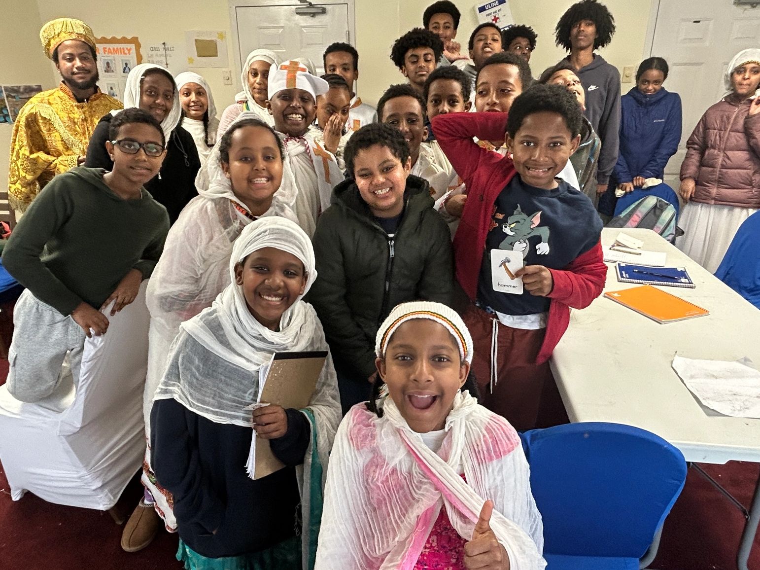 Group of children and an adult smiling indoors.