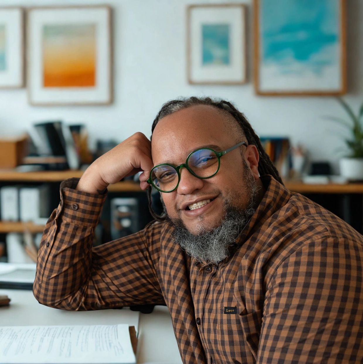 Smiling man with glasses and beard in a cozy office setting.