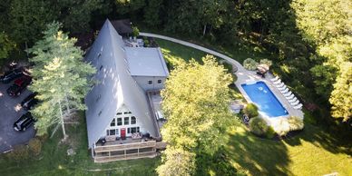 A-frame house with a pool surrounded by trees and greenery.