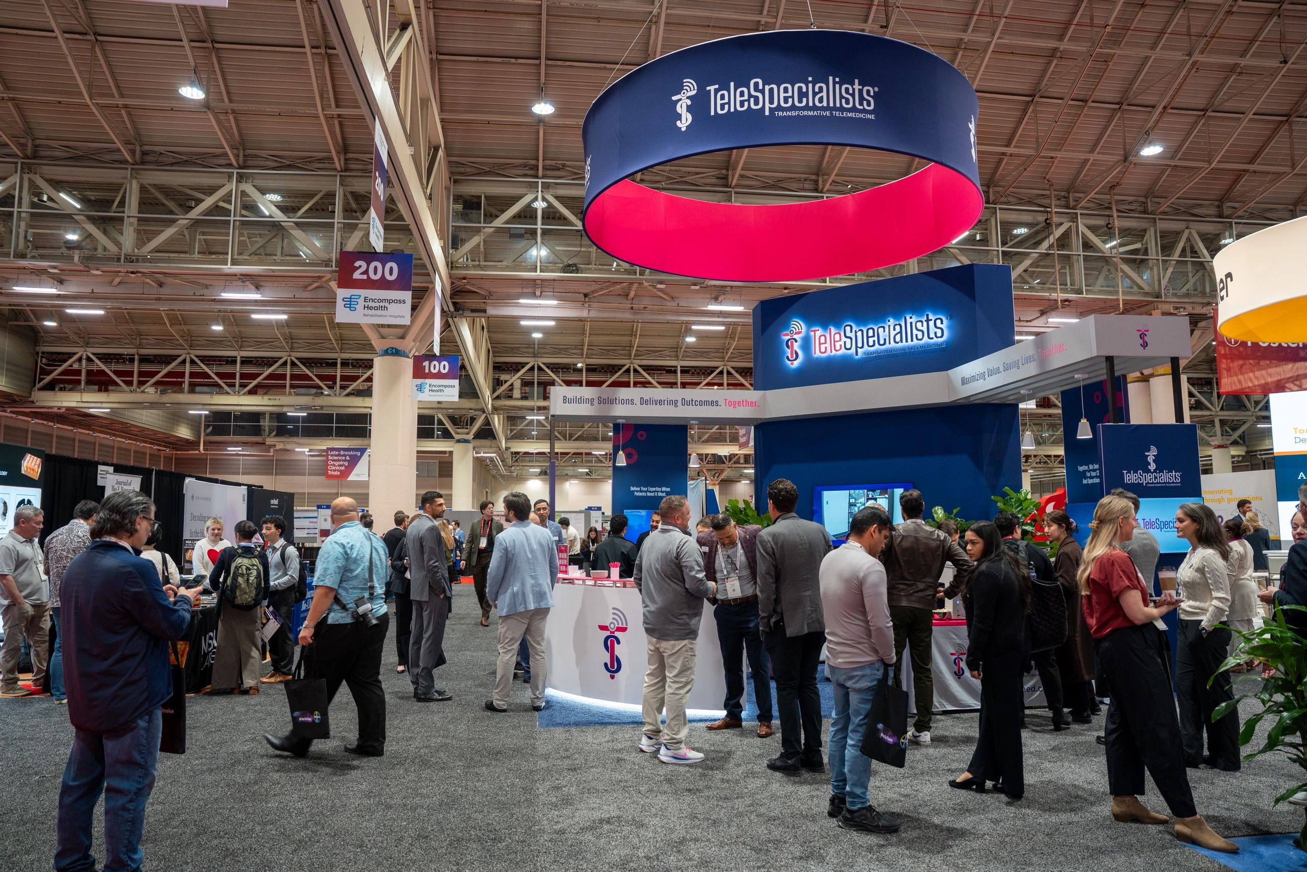 Busy trade show floor with TeleSpecialists booth and many attendees networking.