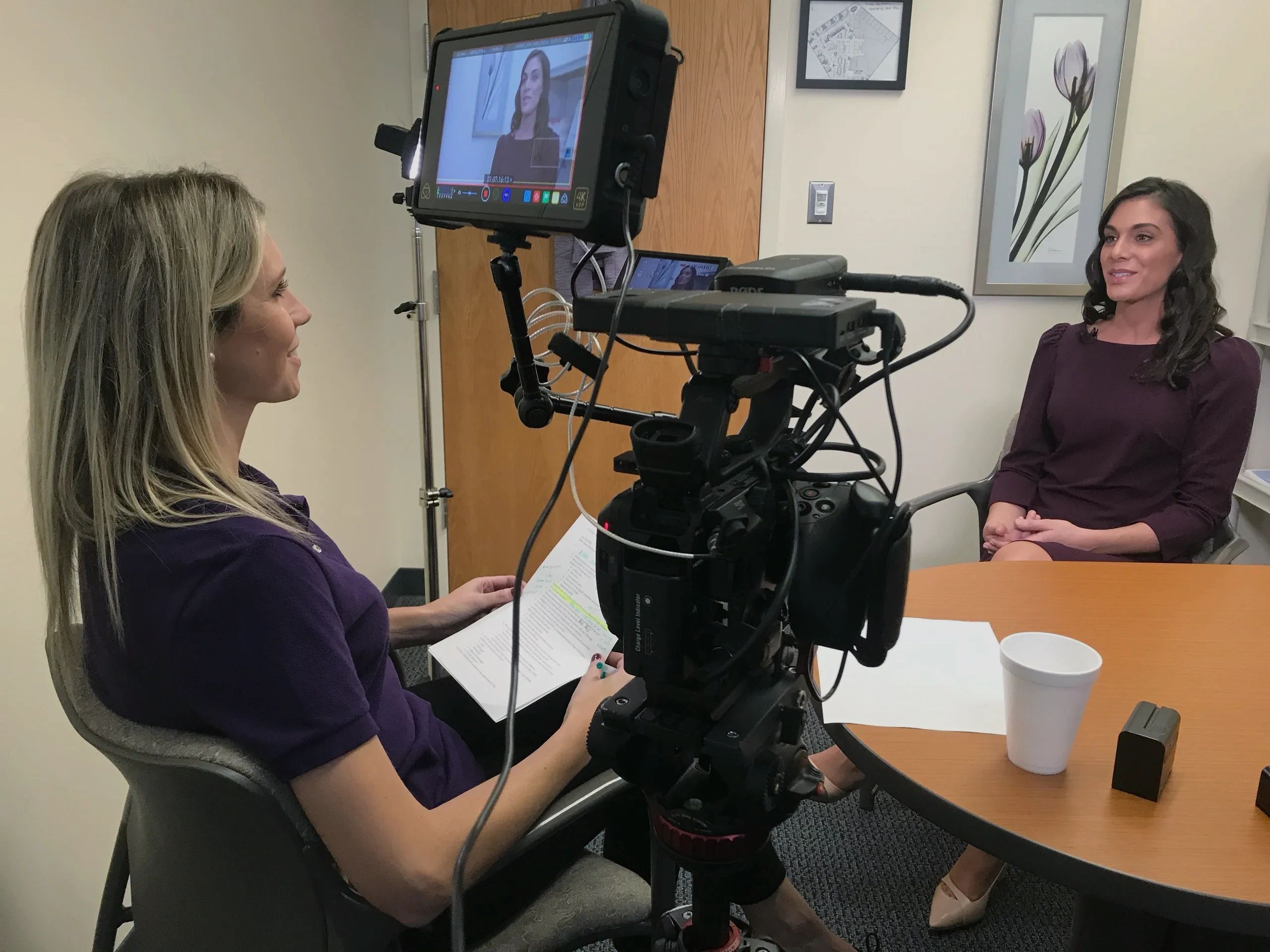Two women engaged in a recorded interview in an office setting.