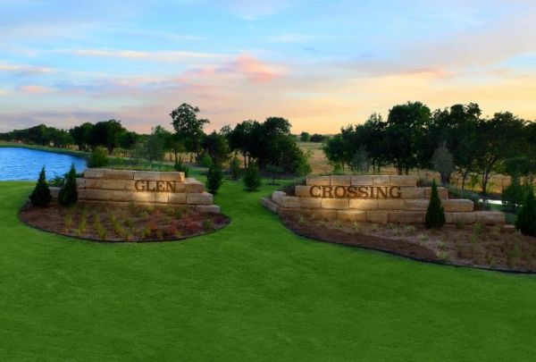 Stone signs reading 'Glen Crossing' at a landscaped entrance near a pond.