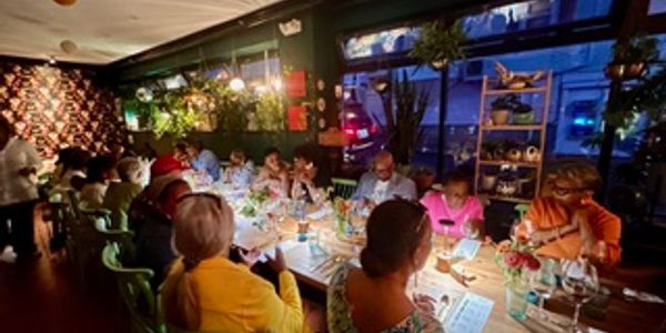 Group dining in a cozy, warmly lit restaurant with large windows.