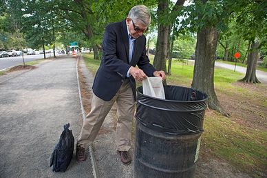 Michael Dukakis, the 1988 Democratic presidential nominee, empties a grocery bag of trash.