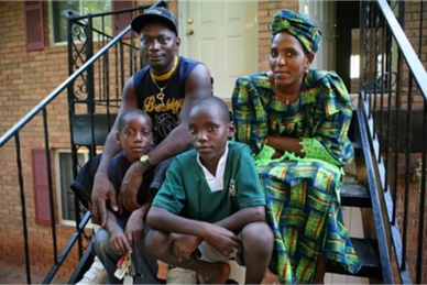 A Congolese-Rwandan refugee family sits on apartment steps